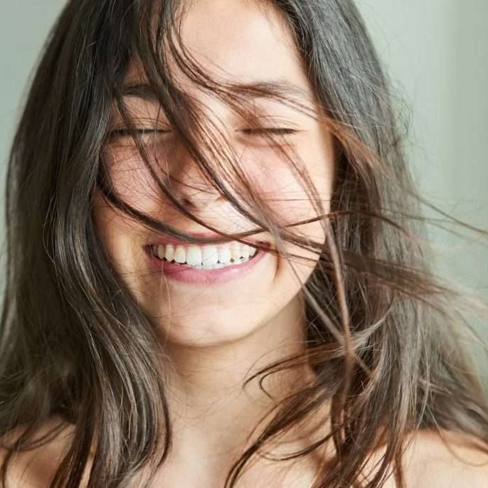 Close-up portrait of a beautiful girl smiling with her hair blowing in wind